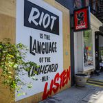 A sign reads: "Riot is the language of the unheard"